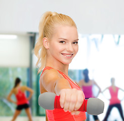 Image showing smiling beautiful sporty woman with dumbbell