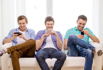 Image showing smiling friends with smartphones at home