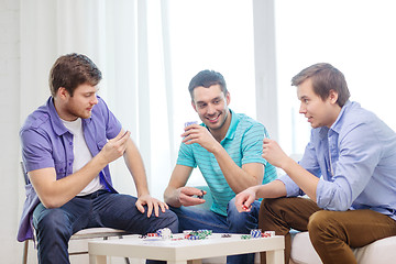 Image showing happy three male friends playing poker at home