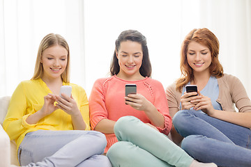 Image showing smiling teenage girls with smartphones at home