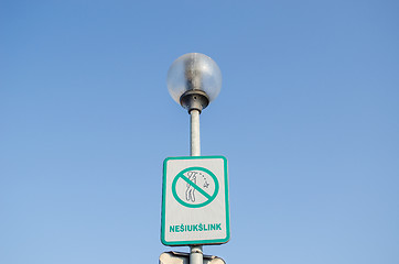 Image showing warning sign on littering streets on street lamp 