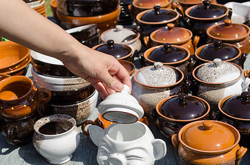 Image showing handmade clay pots and woman hand hold clay lit  