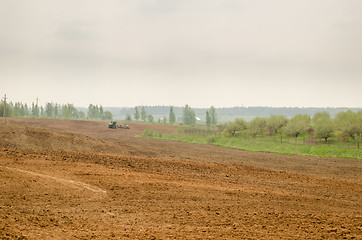 Image showing wide plowed field in rural image with tractor  