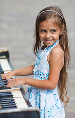 Image showing Little girl playing on a piano