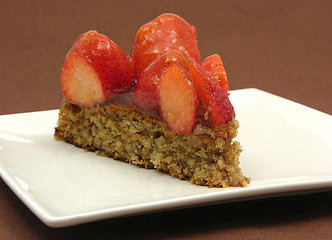Image showing One slice of strawberry cake on white plate an brown background