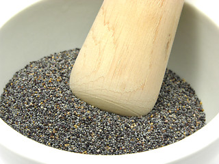 Image showing Pestling poppy seeds  in a bowl of chinaware