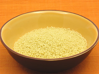 Image showing Yellow couscous in a orange bowl of ceramic on an orange background