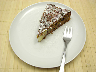 Image showing One slice of pear cake on a white plate dusted with powder sugar