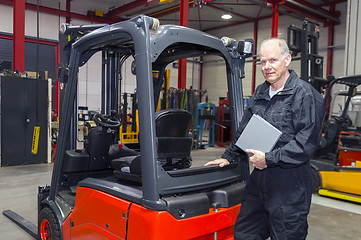 Image showing Forklift mechanic with manual