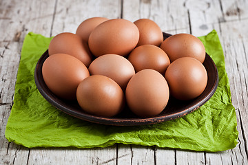 Image showing  fresh brown eggs in plate and green napkin