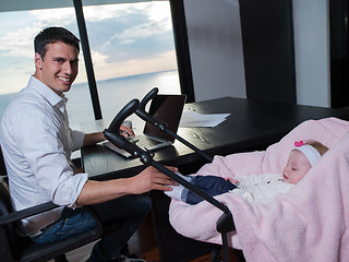 Image showing man working from home and take care of baby