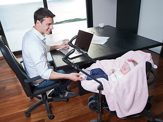 Image showing man working from home and take care of baby