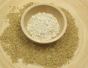 Image showing Wooden bowl with oat flakes and corn on bamboo plate