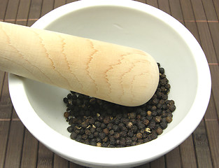 Image showing Pestling black peppercorns  in a bowl of chinaware