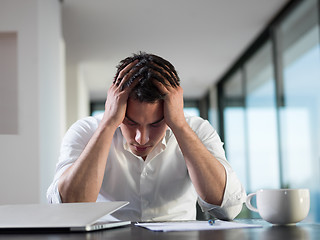 Image showing frustrated young business man working on laptop computer at home