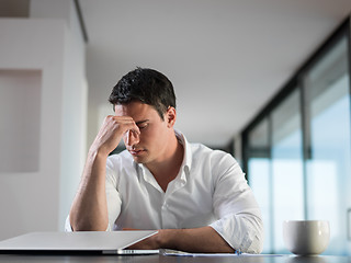 Image showing frustrated young business man working on laptop computer at home