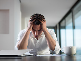 Image showing frustrated young business man working on laptop computer at home