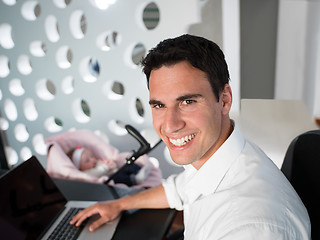 Image showing man working from home and take care of baby