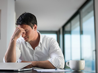 Image showing frustrated young business man working on laptop computer at home