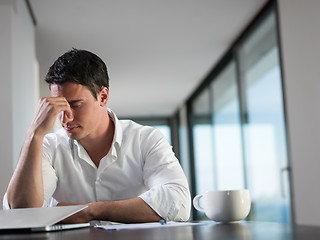 Image showing frustrated young business man working on laptop computer at home