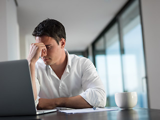 Image showing frustrated young business man working on laptop computer at home