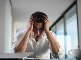 Image showing frustrated young business man working on laptop computer at home