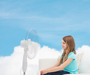 Image showing smiling little girl with big fan at home