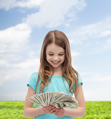 Image showing smiling little girl looking at dollar cash money