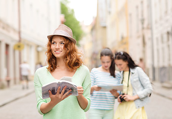 Image showing smiling teenage girls with city guides and camera