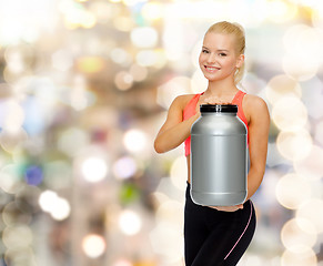 Image showing smiling sporty woman with jar of protein