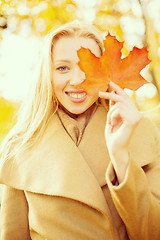 Image showing woman with red marple leaf in the autumn park