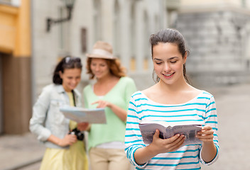 Image showing smiling teenage girls with city guides and camera