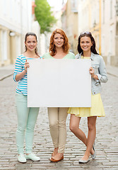 Image showing smiling teenage girls with blank billboard