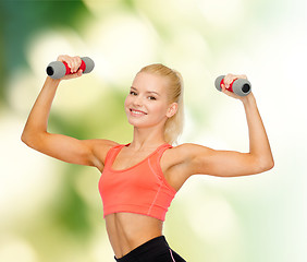 Image showing smiling beautiful sporty woman with dumbbells