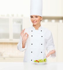 Image showing smiling female chef with salad on plate