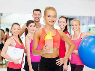 Image showing smiling sporty woman with protein shake bottle