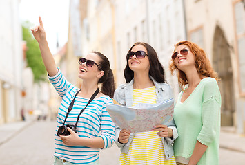 Image showing smiling teenage girls with map and camera