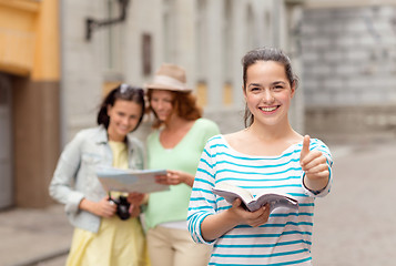 Image showing smiling teenage girls with city guide and camera