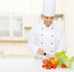 Image showing smiling female chef chopping vegetables