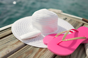 Image showing close up of hat, sunscreen and slippers at seaside