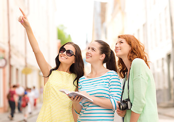 Image showing smiling teenage girls with city guide and camera