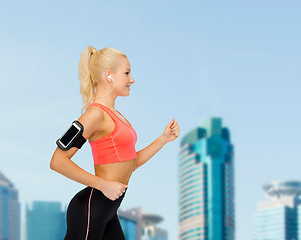 Image showing sporty woman running with smartphone and earphones