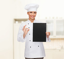 Image showing smiling female chef with black blank paper