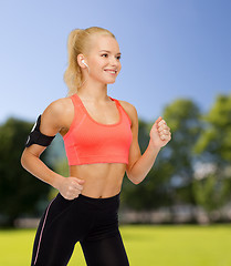 Image showing sporty woman running with smartphone and earphones