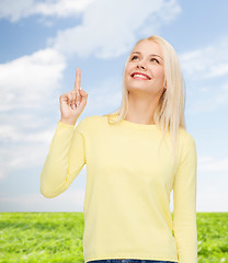 Image showing smiling woman pointing her finger up