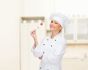 Image showing smiling female chef with fork and tomato