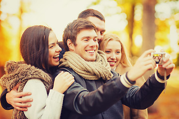 Image showing group of friends with photo camera in autumn park