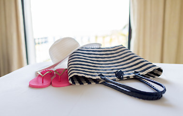 Image showing close-up of beach bag, hat and flip-flop on bed