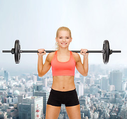 Image showing smiling sporty woman exercising with barbell