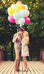 Image showing couple with colorful balloons kissing in the park